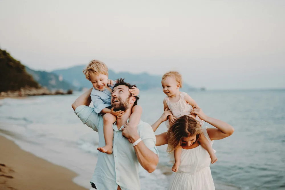 Familia con dos hijos paseando juntos por la orilla del mar