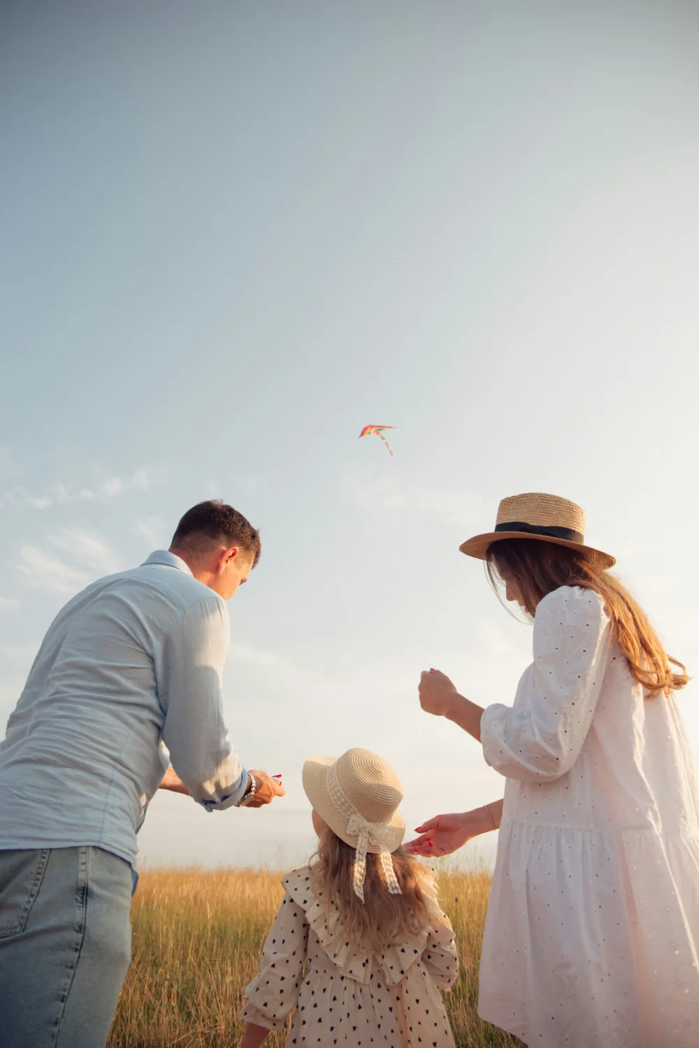 Familia volando una cometa en el campo al atardecer