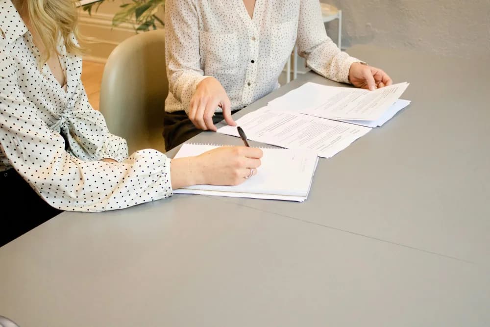 Dos personas revisando y firmando unos papeles sobre la mesa
