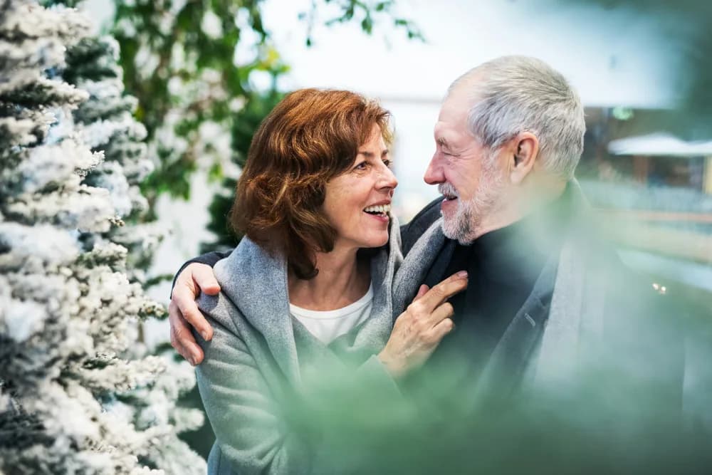 Pareja mayor abrazada entre abetos nevados